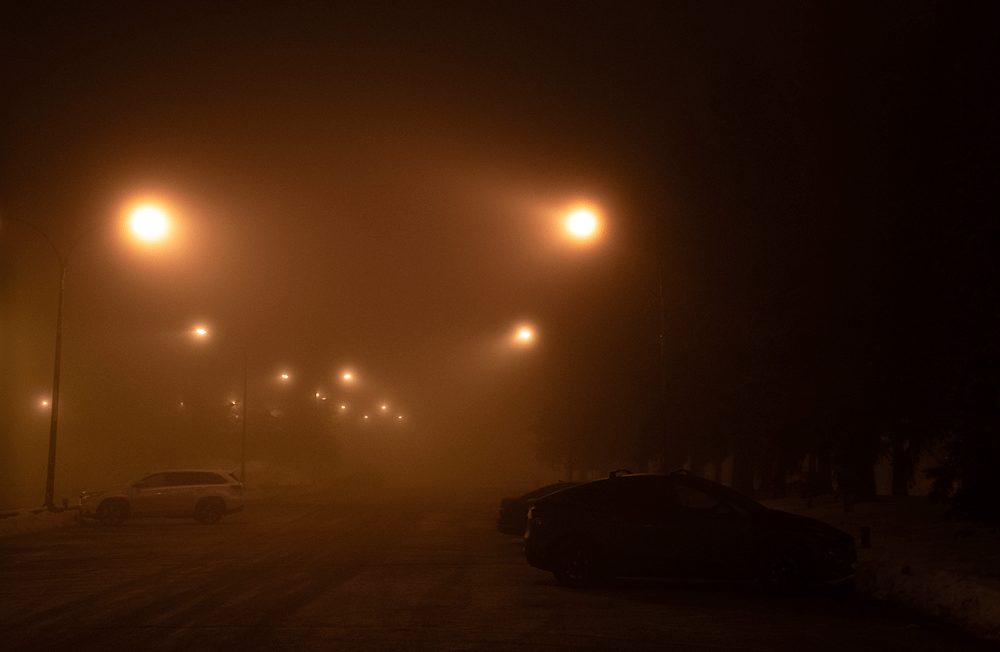A young man in a black jacket and sunglasses on a runway.