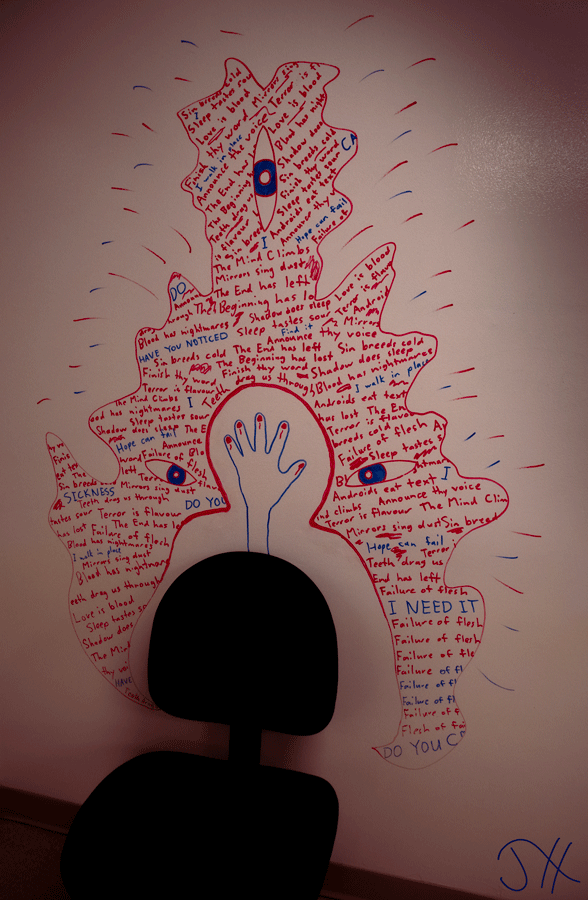 A desk chair sitting in front of a whiteboard wall covered in marker text in the shape of a dark figure behind a person's silhouette.