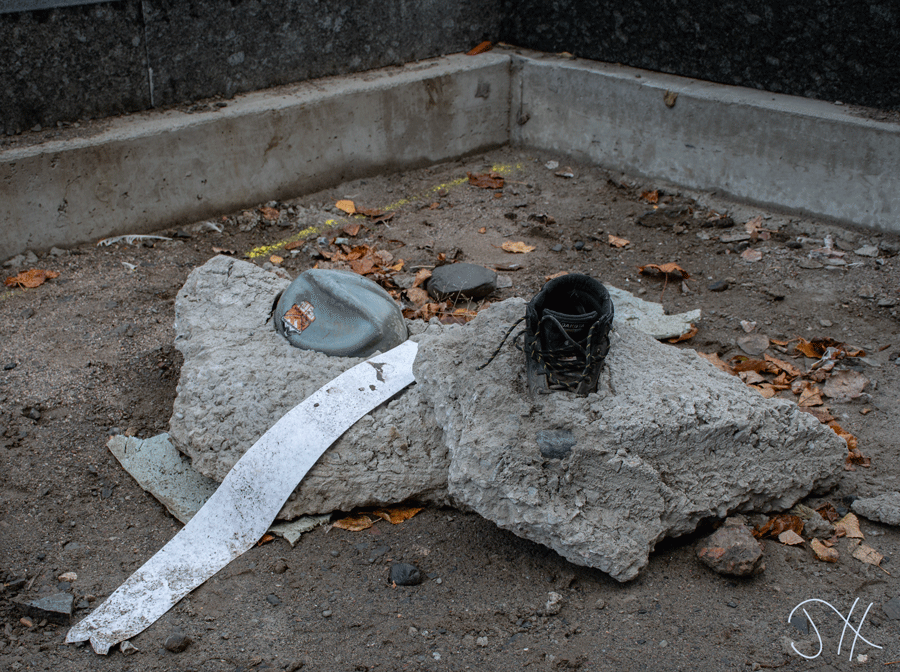 A construction worker's hard hat and boot encased in concrete.