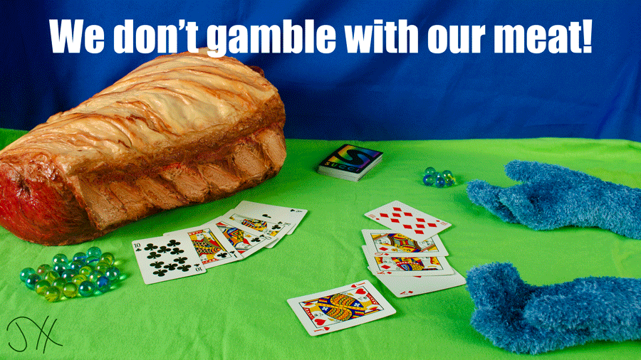 A piece of large plastic meat on a poker table across from a pair of fuzzy blue hands, with a winning poker hand in front of the meat. The words 'We don't gamble with our meat' are written across the top.